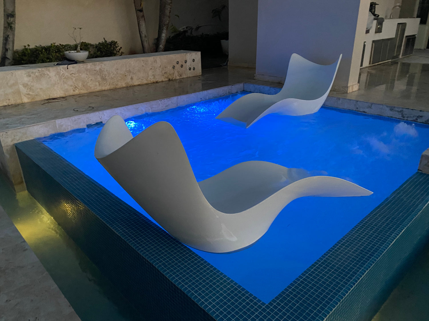 Deck moderno en piscina, con sillas "lounge chairs" en patio